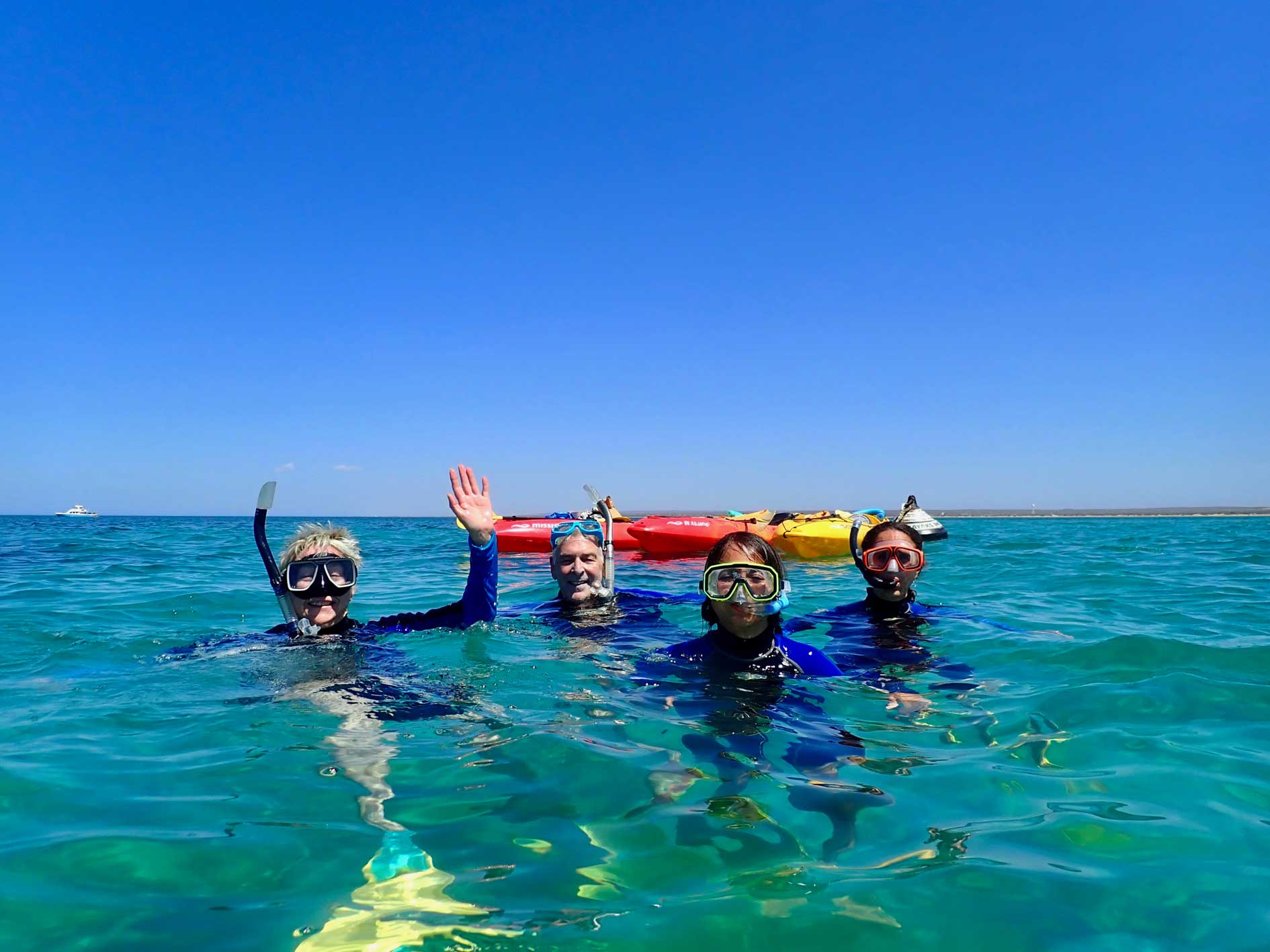 Snorkellers in the water with kayaks behind them on sea kayak and snorkel tour Turtle Tour at Ningaloo Reef, Exmouth, Western Australia