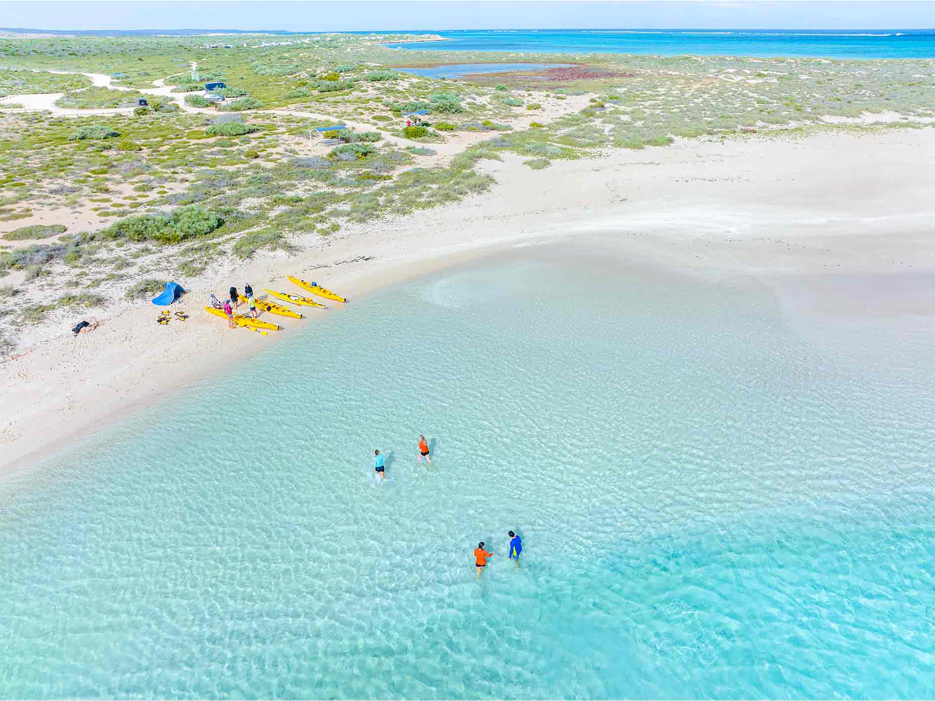 Couple paddle a double sea kayak across turquoise water on overnight sea kayaking, snorkelling, camping tour at Ningaloo Reef, Exmouth, Western Australia