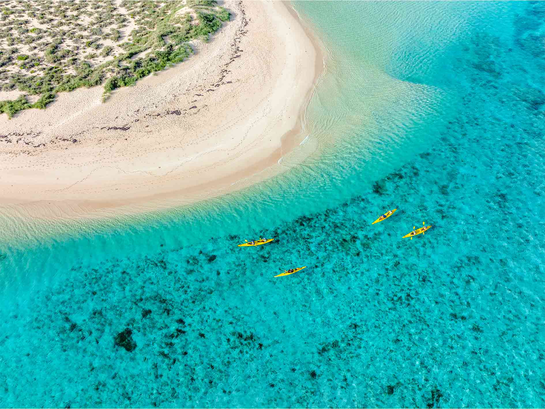 Smiling lady paddling a sea kayak on Lagoon Explorer day tour at Ningaloo Reef, Exmouth, Western Australia